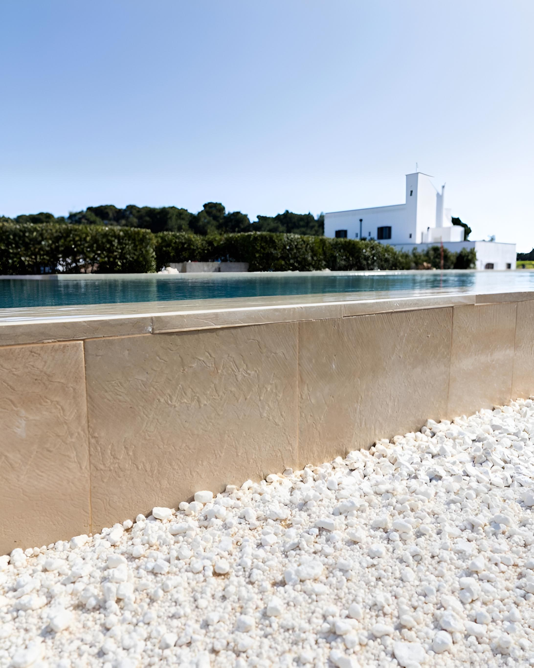 Una piscina blu scintillante circondata da sedie a sdraio e palme